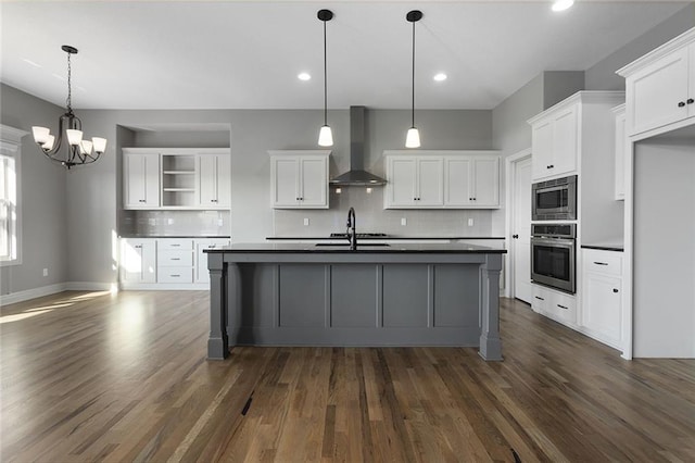 kitchen with wall chimney range hood, decorative light fixtures, stainless steel appliances, and white cabinets