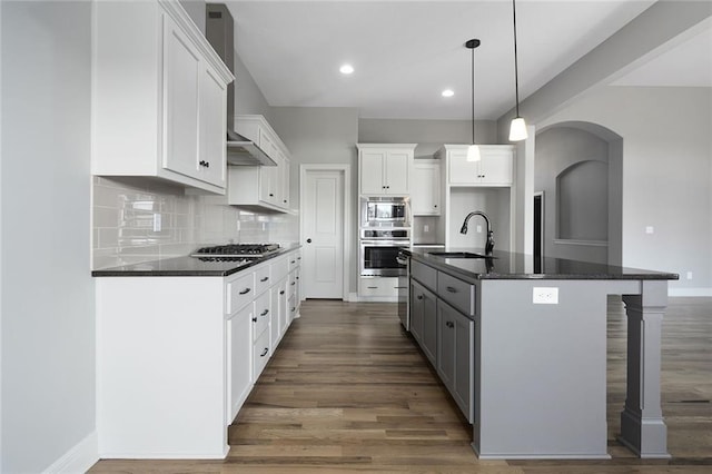 kitchen with sink, dark wood-type flooring, an island with sink, and white cabinets