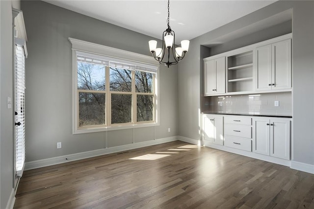 unfurnished dining area featuring dark wood-type flooring and a notable chandelier