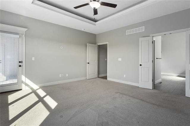 carpeted empty room with ceiling fan and a tray ceiling