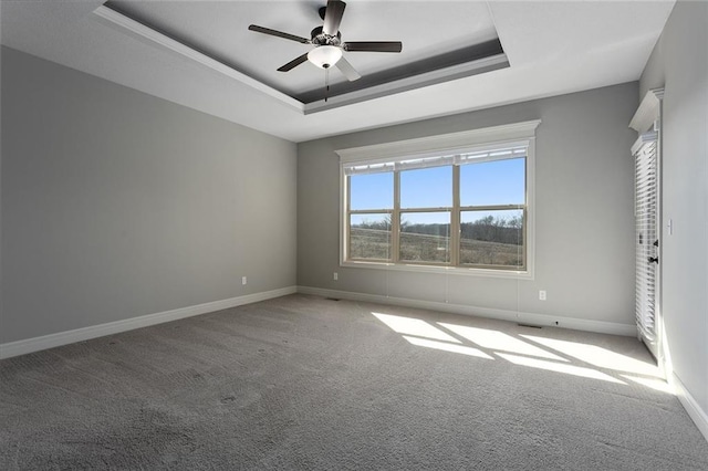 spare room featuring a raised ceiling, carpet, and ceiling fan