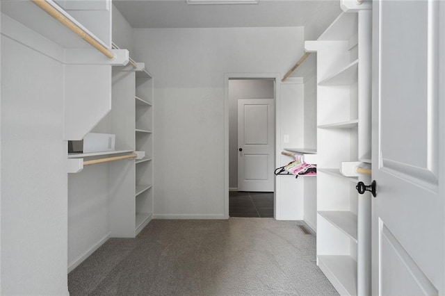 walk in closet featuring dark carpet