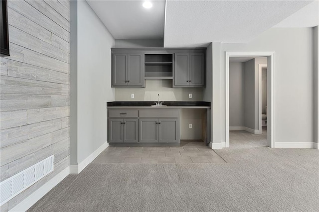 kitchen featuring sink, gray cabinetry, and light colored carpet