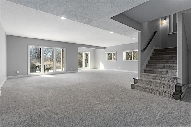 unfurnished living room featuring plenty of natural light, a textured ceiling, and carpet