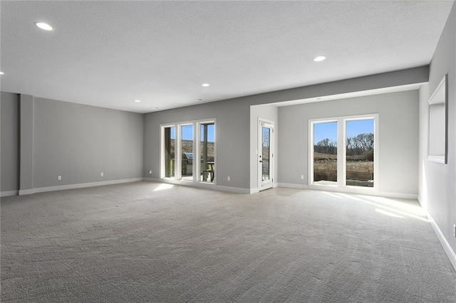 spare room with light colored carpet and a textured ceiling