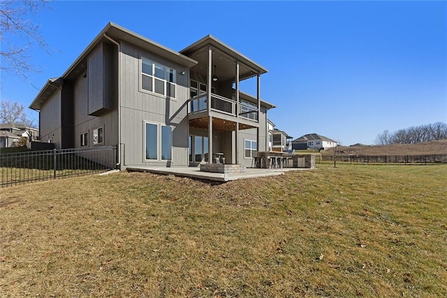 back of property with a balcony, a patio, and a lawn