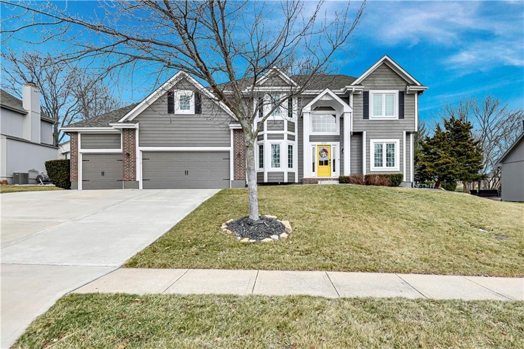 2321 SW Waterfall Dr, Lees Summit, MO 64081 - traditional home featuring brick siding, central AC, a front yard, concrete driveway, and an attached garage