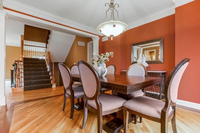 dining room with ornamental molding and light hardwood / wood-style floors