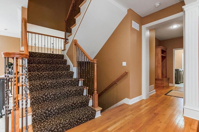 stairway featuring wood-type flooring and ornate columns