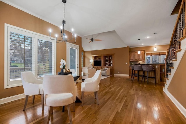 dining room featuring hardwood / wood-style flooring, lofted ceiling, and ceiling fan with notable chandelier