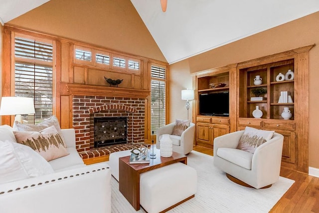 living room with a brick fireplace, light hardwood / wood-style flooring, and high vaulted ceiling