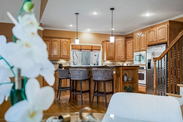 kitchen featuring pendant lighting, crown molding, a breakfast bar, appliances with stainless steel finishes, and tasteful backsplash