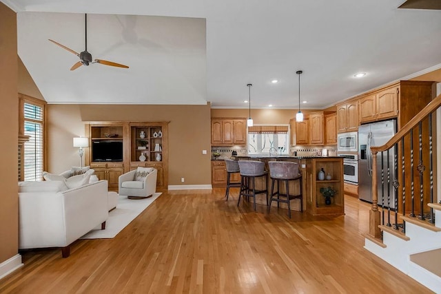 kitchen featuring light hardwood / wood-style flooring, a breakfast bar area, stainless steel appliances, a center island, and decorative light fixtures