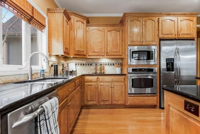 kitchen with sink, crown molding, stainless steel appliances, decorative backsplash, and dark stone counters