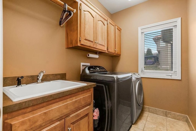 clothes washing area with sink, light tile patterned floors, cabinets, and washing machine and clothes dryer