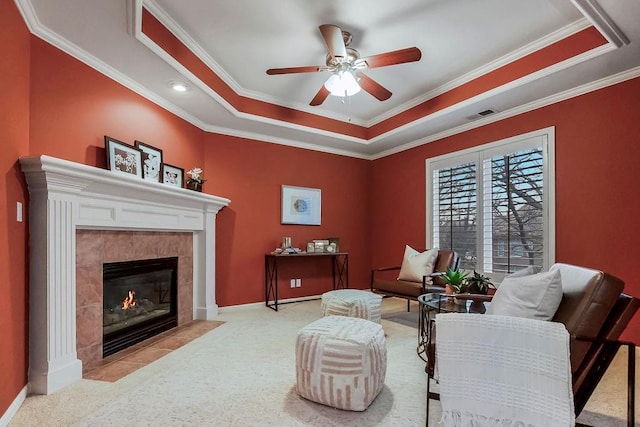 living room with crown molding, a tray ceiling, and a tiled fireplace