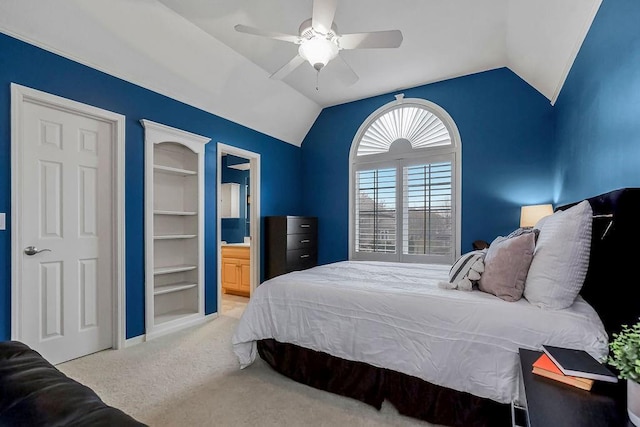 bedroom featuring ceiling fan, light colored carpet, lofted ceiling, and ensuite bath