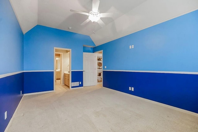 interior space with light carpet, ensuite bath, vaulted ceiling, and ceiling fan