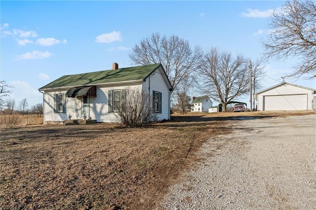 exterior space with a garage, a chimney, and an outdoor structure