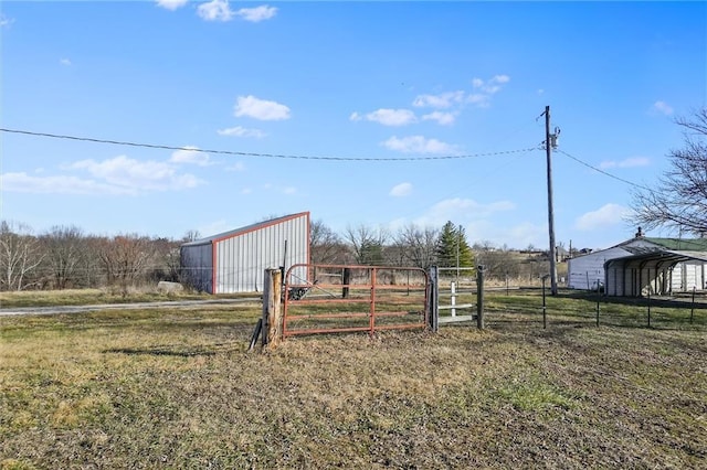 view of yard with an outbuilding, a gate, fence, an outdoor structure, and a carport