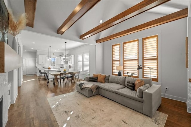 living room with hardwood / wood-style flooring, an inviting chandelier, and lofted ceiling with beams