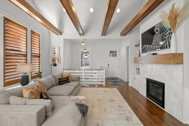 living room featuring a tile fireplace, dark wood-type flooring, and beam ceiling