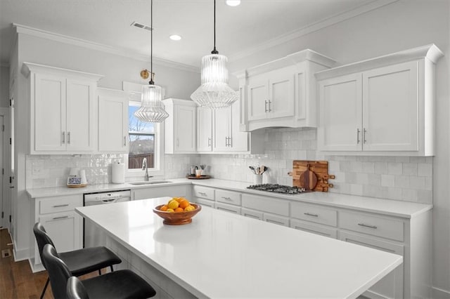 kitchen featuring pendant lighting, sink, appliances with stainless steel finishes, white cabinetry, and ornamental molding