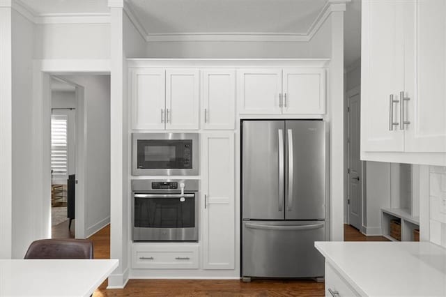 kitchen featuring white cabinetry, ornamental molding, and appliances with stainless steel finishes