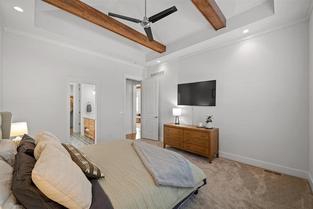 bedroom featuring ceiling fan, light colored carpet, beam ceiling, and ensuite bath