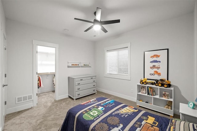 carpeted bedroom with a walk in closet and ceiling fan