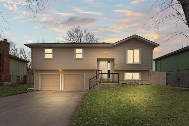 bi-level home featuring a garage and a yard