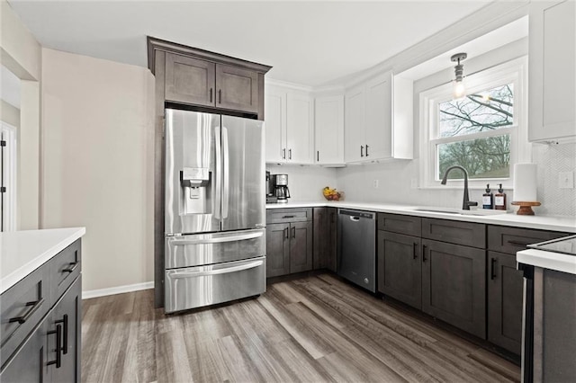 kitchen featuring sink, white cabinetry, hanging light fixtures, stainless steel appliances, and dark hardwood / wood-style flooring