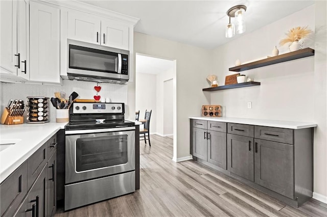 kitchen with appliances with stainless steel finishes, white cabinets, light wood-type flooring, and decorative backsplash