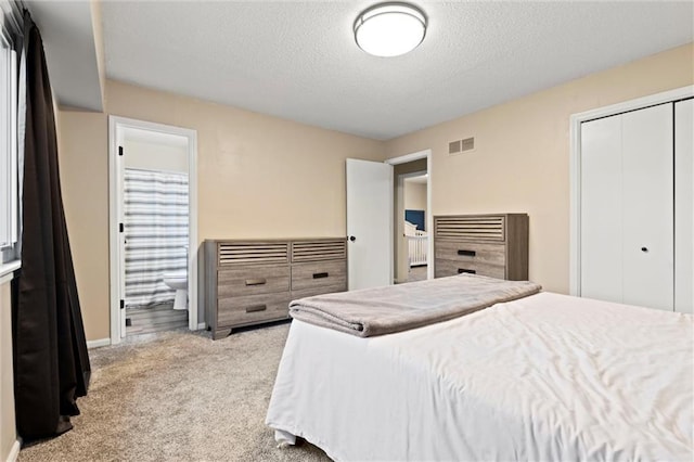 bedroom featuring light carpet, ensuite bath, a closet, and a textured ceiling