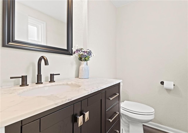 bathroom with hardwood / wood-style flooring, vanity, and toilet