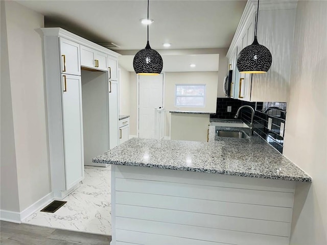 kitchen featuring white cabinetry, sink, light stone countertops, and kitchen peninsula