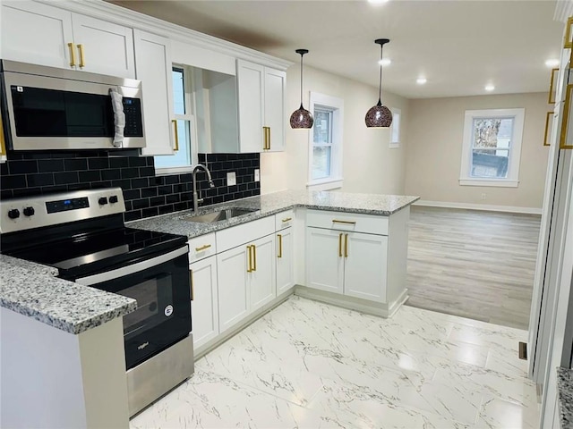 kitchen with sink, white cabinetry, hanging light fixtures, appliances with stainless steel finishes, and light stone countertops