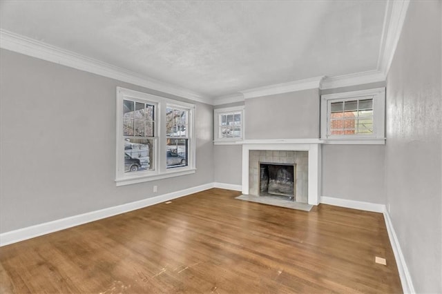 unfurnished living room featuring ornamental molding, wood finished floors, a tile fireplace, and baseboards