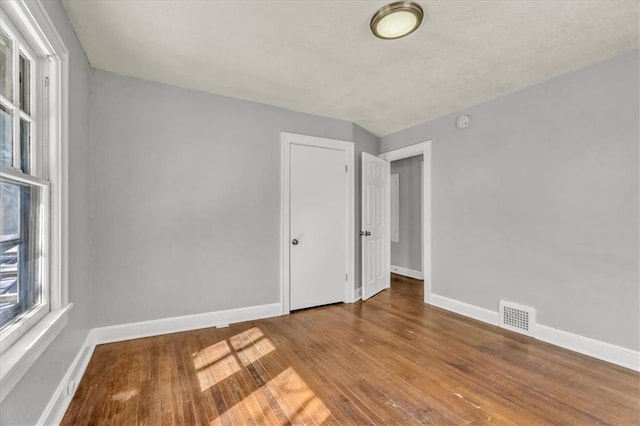 spare room featuring baseboards, visible vents, and wood finished floors