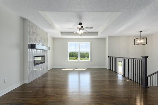 1320 N Holland Ct, Independence, MO 64056 - unfurnished living room featuring wood finished floors, ceiling fan, a large fireplace, a raised ceiling, and a textured ceiling
