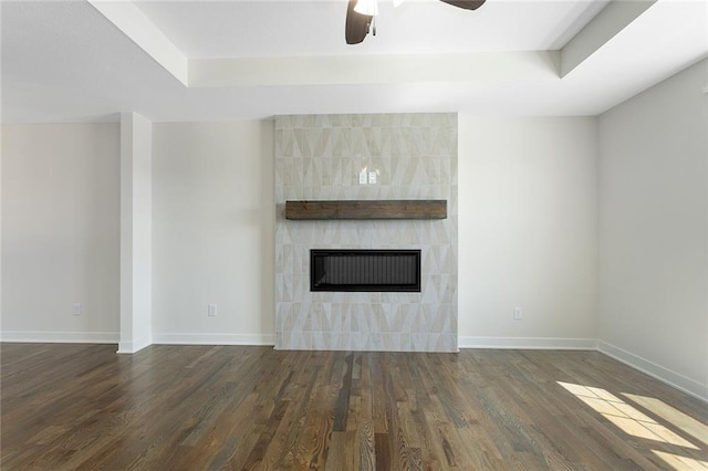 1320 N Holland Ct, Independence, MO 64056 - unfurnished living room with wood finished floors, a ceiling fan, a raised ceiling, and a tiled fireplace
