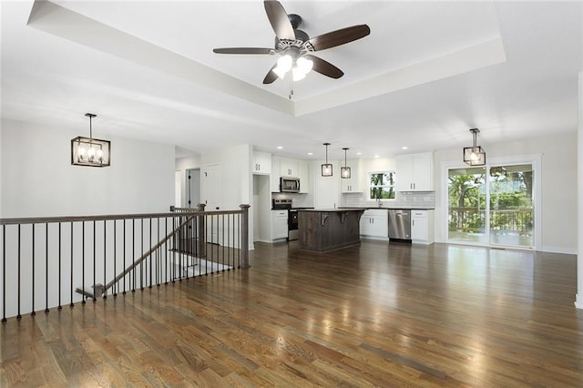 1320 N Holland Ct, Independence, MO 64056 - unfurnished living room featuring dark wood-style floors, a chandelier, a tray ceiling, ceiling fan, and recessed lighting