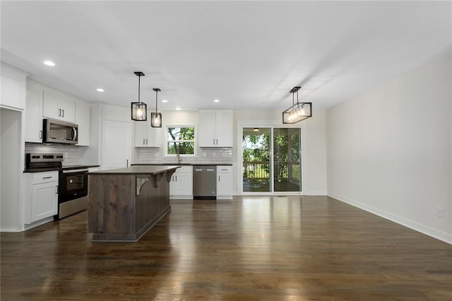 1320 N Holland Ct, Independence, MO 64056 - kitchen with stainless steel appliances, backsplash, dark wood-style floors, dark countertops, and recessed lighting