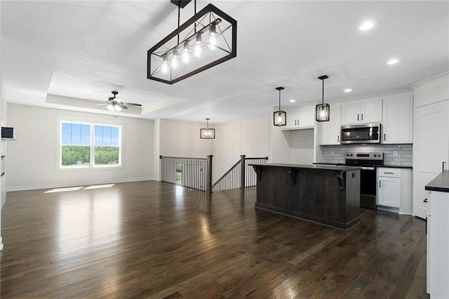 1320 N Holland Ct, Independence, MO 64056 - kitchen featuring appliances with stainless steel finishes, dark countertops, recessed lighting, dark wood-style flooring, and white cabinetry