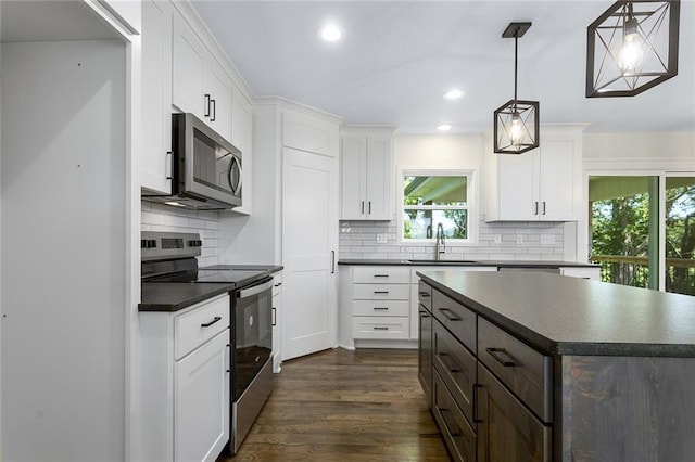 1320 N Holland Ct, Independence, MO 64056 - kitchen with appliances with stainless steel finishes, dark countertops, dark wood-style floors, and recessed lighting
