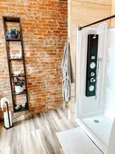 218/220 N Main St, Maryville, MO 64468 - bathroom with hardwood / wood-style flooring, brick wall, and walk in shower