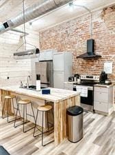 218/220 N Main St, Maryville, MO 64468 - kitchen featuring wall chimney exhaust hood, appliances with stainless steel finishes, light wood-type flooring, and white cabinets