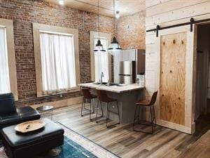 218/220 N Main St, Maryville, MO 64468 - bar featuring brick wall, a barn door, hardwood / wood-style flooring, and pendant lighting