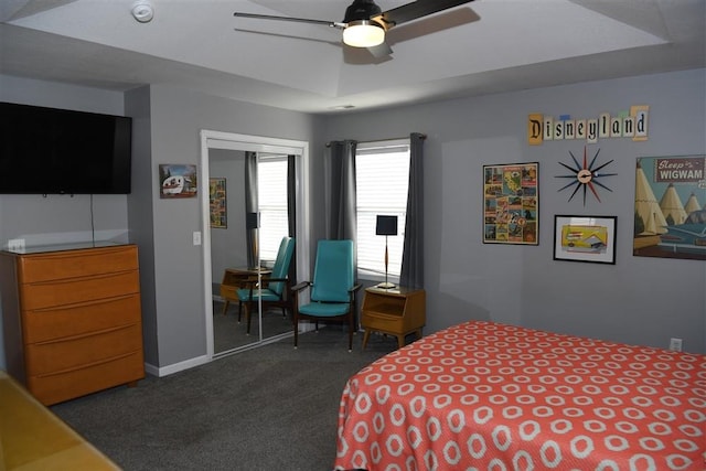 carpeted bedroom with ceiling fan and a tray ceiling