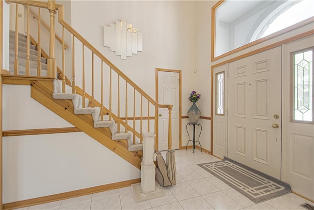 tiled foyer entrance with a towering ceiling, visible vents, stairs, and baseboards